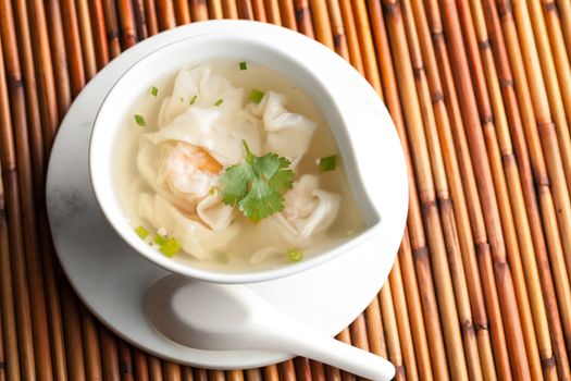 Thai shrimp wonton soup bowl close up with spoon.