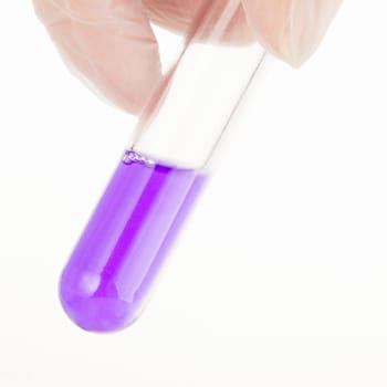 Fingers holding test tube with purple  liquid.