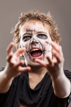Halloween or horror concept - screaming walking dead zombie child boy reaching hand
