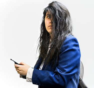 Side shot of latina teen girl with a backpck on, holding a cellphone, and looking of to the side