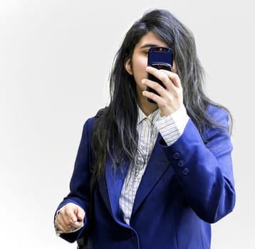 Latina teen girl holding cellphone pointed at camera