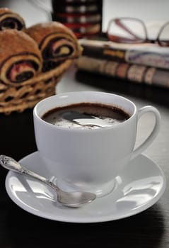 cup of coffee on the table with bread rolls and newspapers