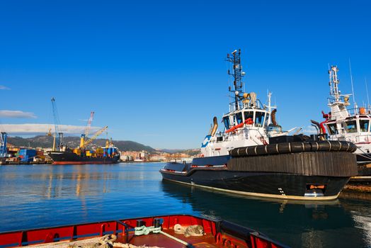 Two tugboats and containers ship docked in the harbor of La Spezia, Liguria, Italy