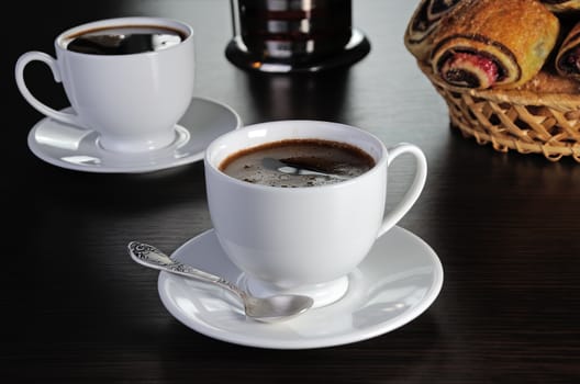 cup of coffee on the table with buns in a basket