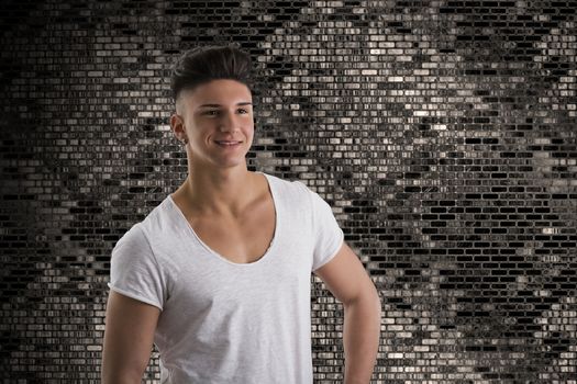 Attractive trendy young man standing on metallic background smiling and looking away