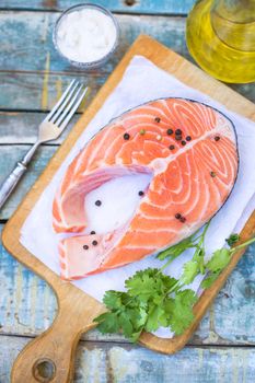 piece of raw red fish with parsley, pepper and olive oil