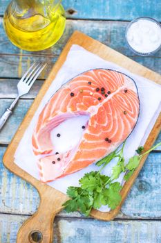 piece of raw red fish with parsley, pepper and olive oil