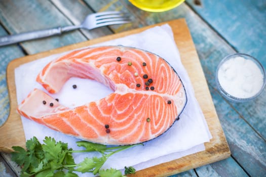 piece of raw red fish with parsley, pepper and olive oil