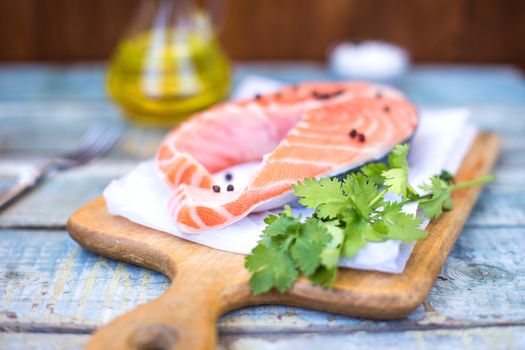 piece of raw red fish with parsley, pepper and olive oil