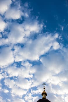 The cross of the orthodox Christian church against the cloudy sky background.