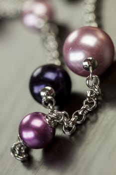 Close up of three attractive shiny purple beads attached by silver chains on an item of jewellery in a fashion and handicraft concept