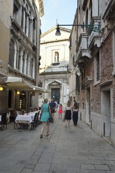 Tourists walk along a street in Venice, Italy, where is situated the church of San Silvestro