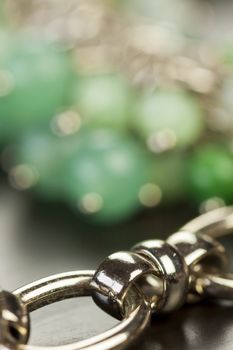 Close up view of pretty translucent green beads on an item of silver jewellery attached in a bunch to a ring by short chains with shallow dof in a fashion concept