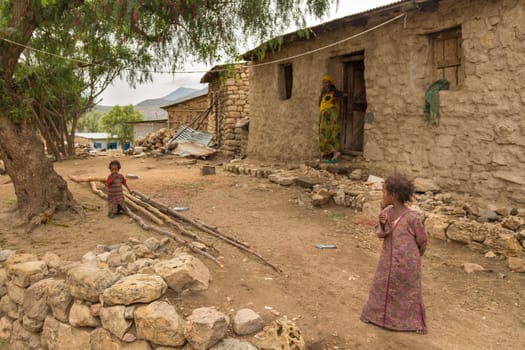 Two little girls play just outside of their homes with their mother watching in the rural regions of Harar, Ethiopia on July 26, 2014