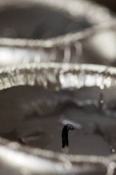 Close up view of the black burnt extinguished wick on a candle surrounded by soft wax with selective focus to the wick