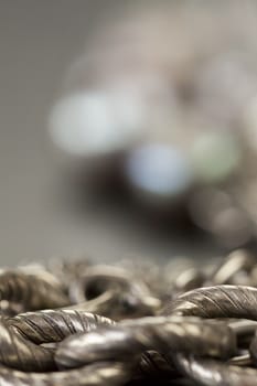 Assorted silver costume jewellery with a jumbled pile of chains with different shaped links, a clear crystal bead and a necklace of round silver beads with focus to the chains