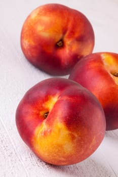 Three tasty fresh ripe juicy nectarines on white painted wooden boards for a healthy snack and diet