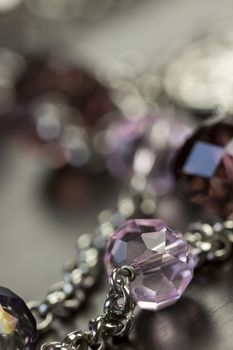 Close up of three attractive shiny purple beads attached by silver chains on an item of jewellery in a fashion and handicraft concept