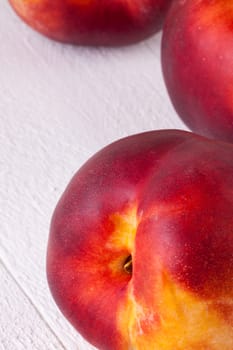 Three tasty fresh ripe juicy nectarines on white painted wooden boards for a healthy snack and diet