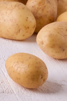 Farm fresh washed whole potatoes for a healthy nutritious cooking ingredient on white painted wooden boards