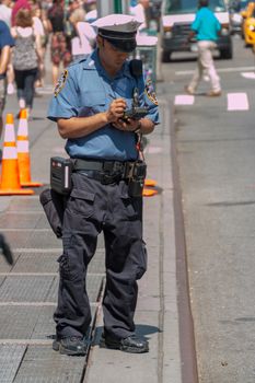 New York - Aug 20: NYPD Traffic officer writes a parking ticket for a parking violation on August 20, 2014 in New York, USA