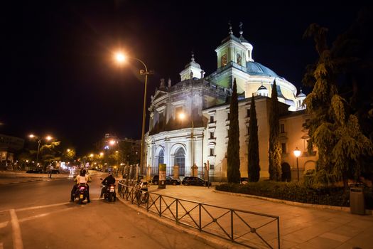 Madrid, Spain - May 6, 2012:  Side view of the Real Basilica de San Francisco el Grande on a sunny spring night and moped bikers on street, Madrid, Spain