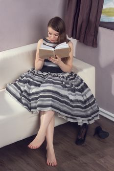 young woman in  dress is reading a book