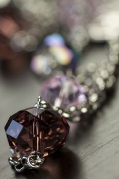 Close up of three attractive shiny purple beads attached by silver chains on an item of jewellery in a fashion and handicraft concept