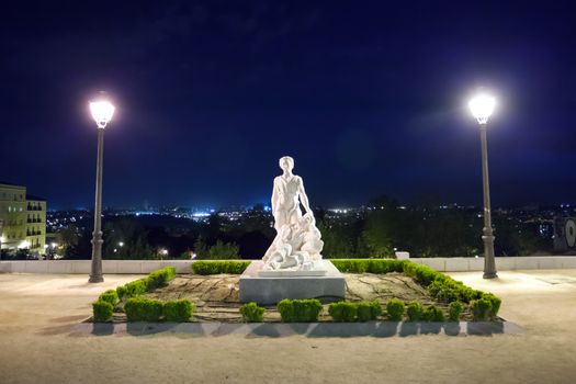Madrid, Spain - May 6, 2012: "The miracle of the angel and San Isidro" sculpture illuminated at night in Dalieda de San Francisco park on a sunny spring day in La Latina, Madrid, Spain