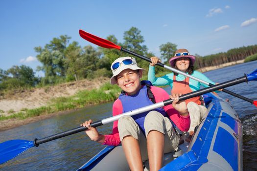 Summer vacation - Cute girl with mother kayaking on river.