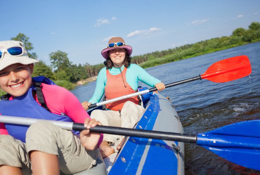 Summer vacation - Happy woman with her daughter kayaking on river.