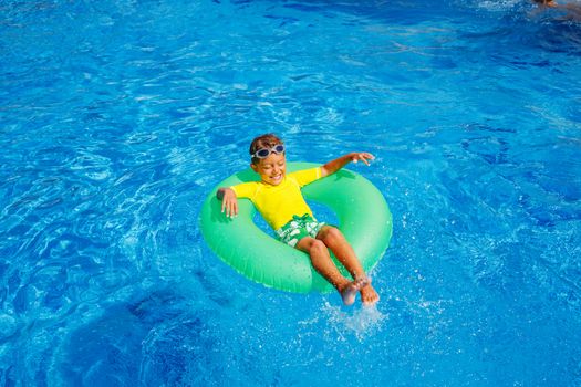 Cute little boy swims in a pool in an green life preserver