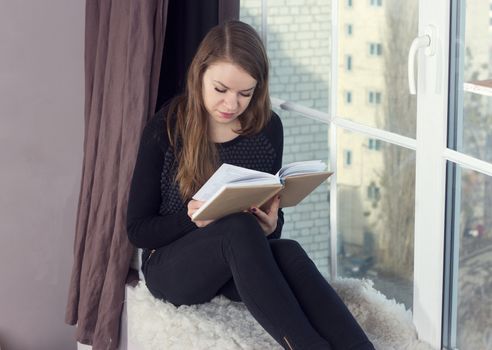 Woman studying at home and looking through the window