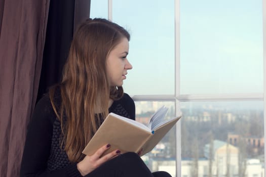 Woman studying at home and looking through the window