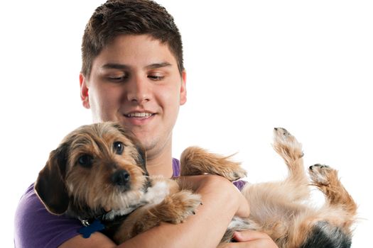 High key portrait of a young man holding a cute mixed breed dog isolated over white. Shallow depth of field with focus on the mans face.