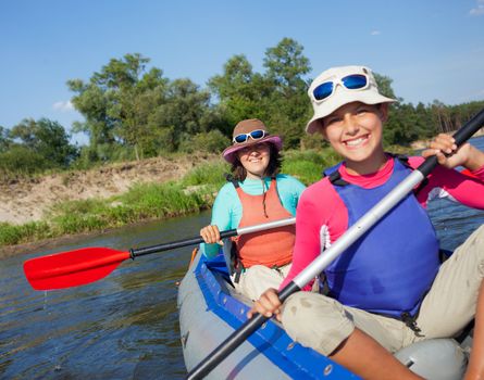 Summer vacation - Happy woman with her daughter kayaking on river.