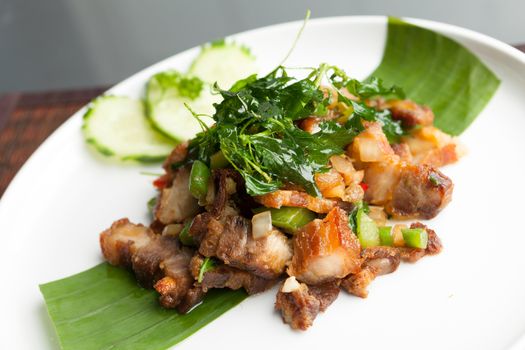 Traditional Thai crispy pork dish with green garnish.