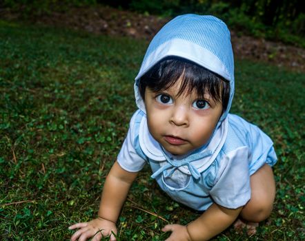 Close up shot of latino baby dressed up and crawling outside in the grass