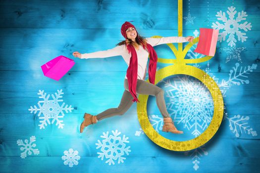 Smiling brunette jumping with gifts bags against christmas decorations over wood