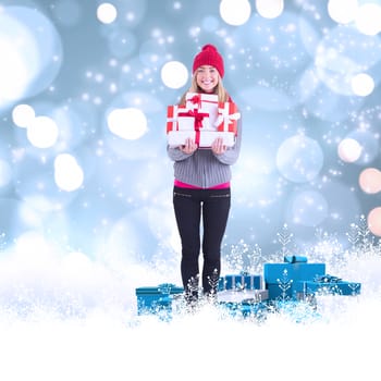 Festive blonde holding pile of gifts against white glowing dots on blue