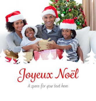 Smiling family sharing Christmas presents against joyeux noel