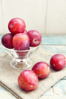 fresh, moist, ripe plums are in a transparent bowl