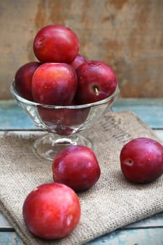 fresh, moist, ripe plums are in a transparent bowl