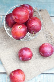 fresh, moist, ripe plums are in a transparent bowl