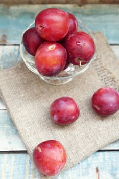 fresh, moist, ripe plums are in a transparent bowl