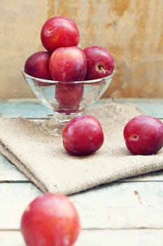 fresh, moist, ripe plums are in a transparent bowl