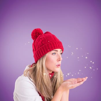 Happy blonde blowing over hands against purple vignette