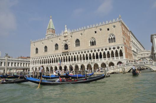 People boating in gondolas at the Grand Canal, next to the Doge Palace,  built in Venetian Gothic style, and one of the main landmarks of the city of Venice, northern Italy. 
