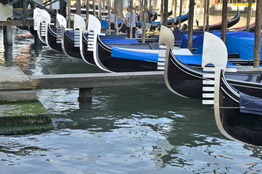 Some people and gondoliers on gondolas parked  in Venice, Italy. 