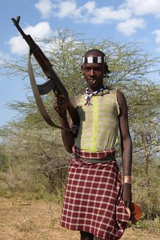 TURMI, ETHIOPIA - NOVEMBER 19, 2014: Young Hamer man with automatic gun on November 19, 2014 in Turmi, Ethiopia.